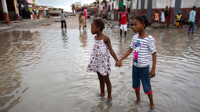 Girls hold hands as they help each other wade through a flooded street after the passing of Hurricane Matthew in Les Cayes, Haiti, Thursday, Oct. 6, 2016. Two days after the storm rampaged across the country’s remote southwestern peninsula, authorities and aid workers still lack a clear picture of what they fear is the country’s biggest disaster in years. (Image: AP)